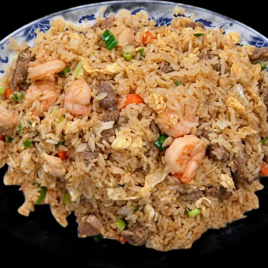 Fried rice with shrimp, beef and chicken on a blue and white platter