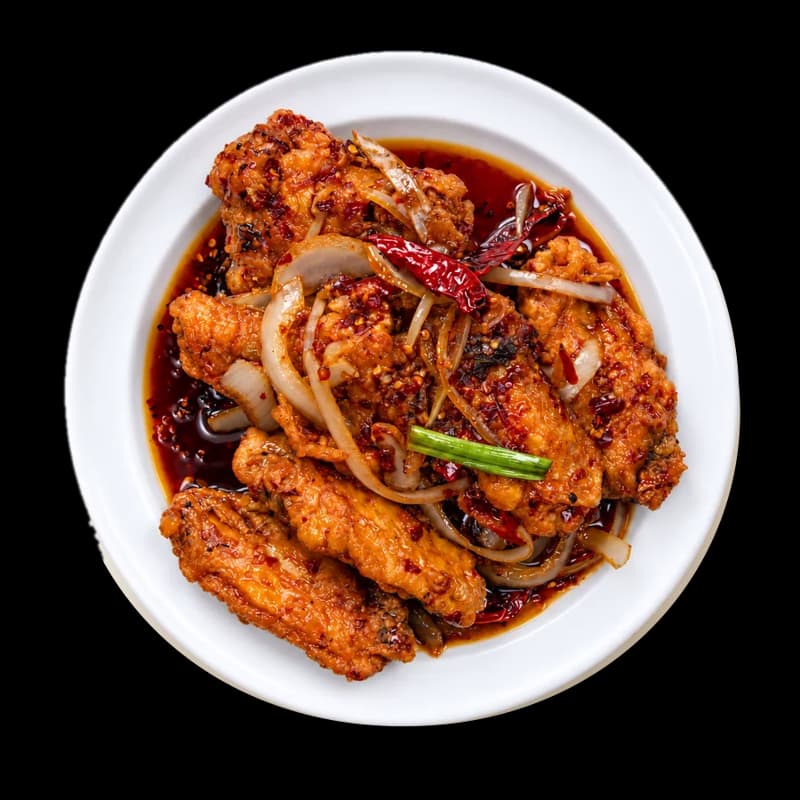 Hot braised chicken wings with onions on a white plate